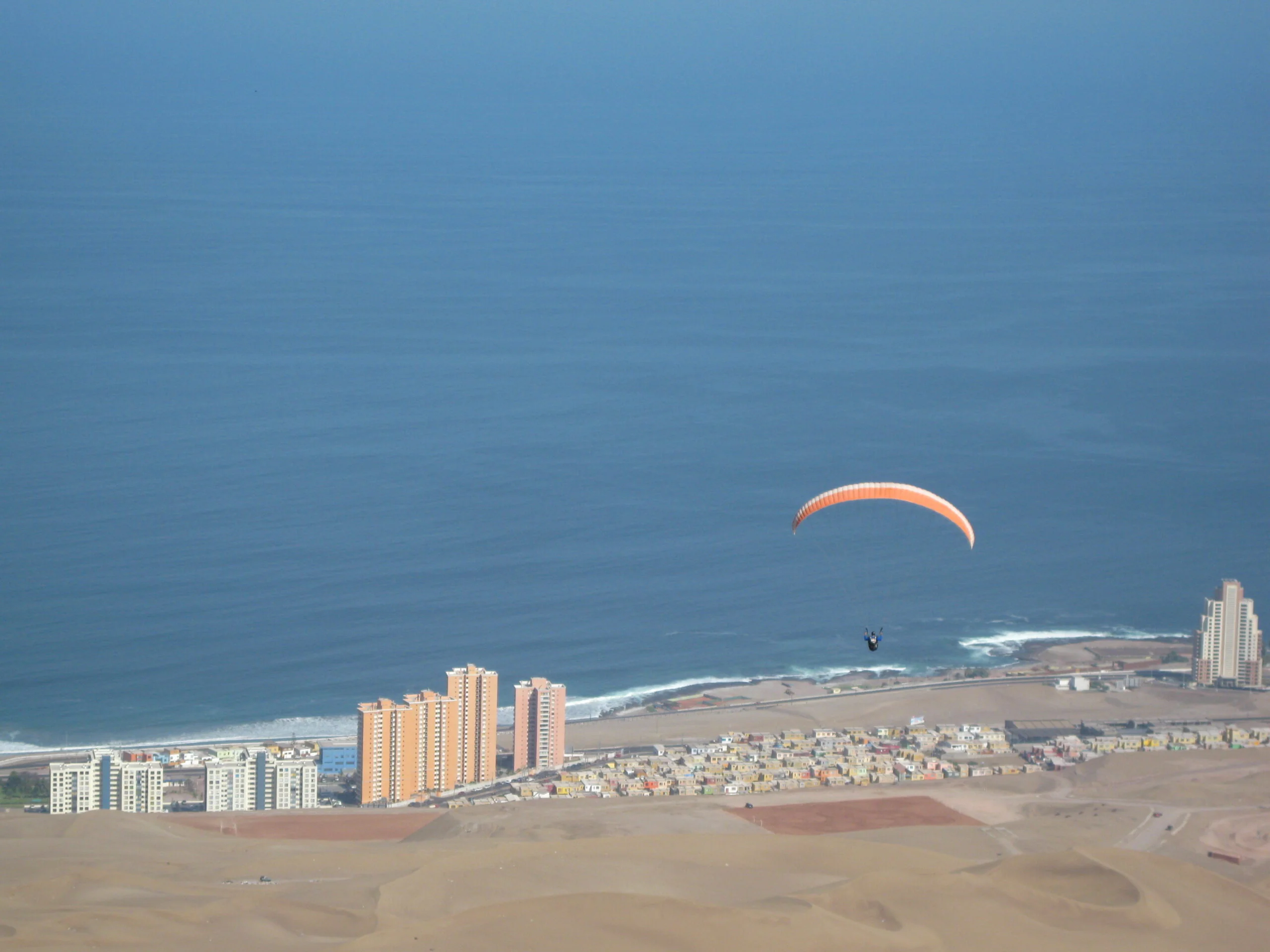 Parapente sobre Iquique con costa y ciudad al fondo
