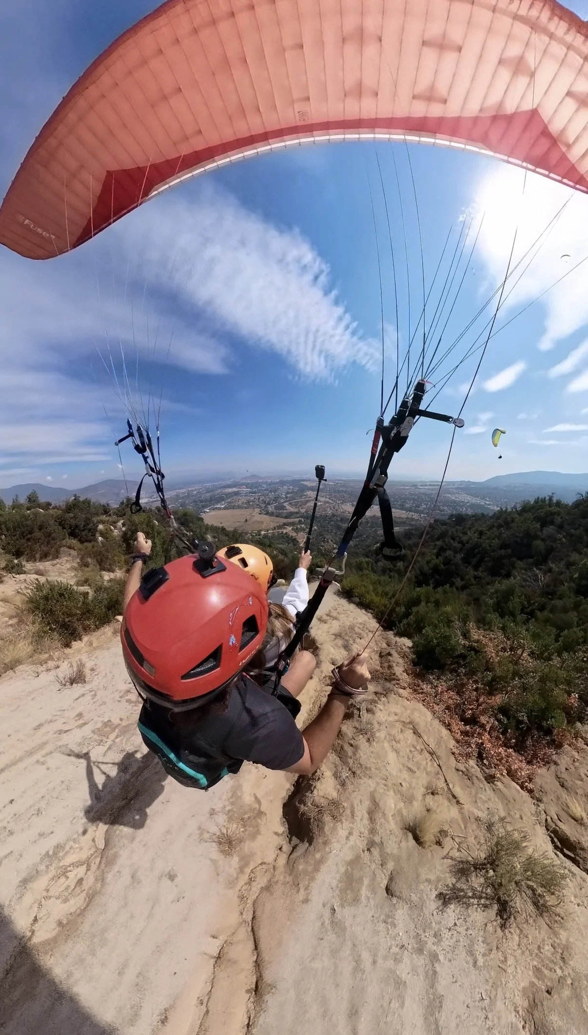 Piloto y pasajera despegan corriendo pendiente abajo en un cerro de Vizcachas, Santiago, con el valle al fondo